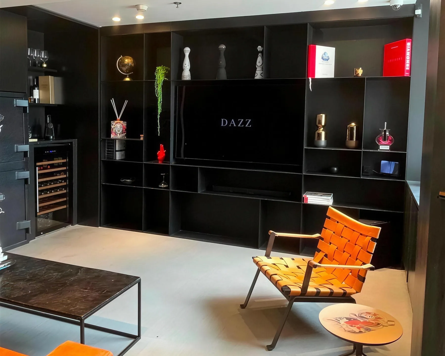 פינת האירוח במשרדי DAZZ בבורסת היהלומים ברמת גן — ספריה שחורה, כורסה וטלוויזיה עם לוגו DAZZ